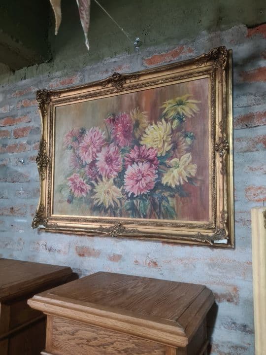 Cuadro con motivos florales y marco dorado tallado.